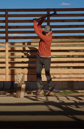 Man wearing a Timberland PRO shirt while chopping wood.